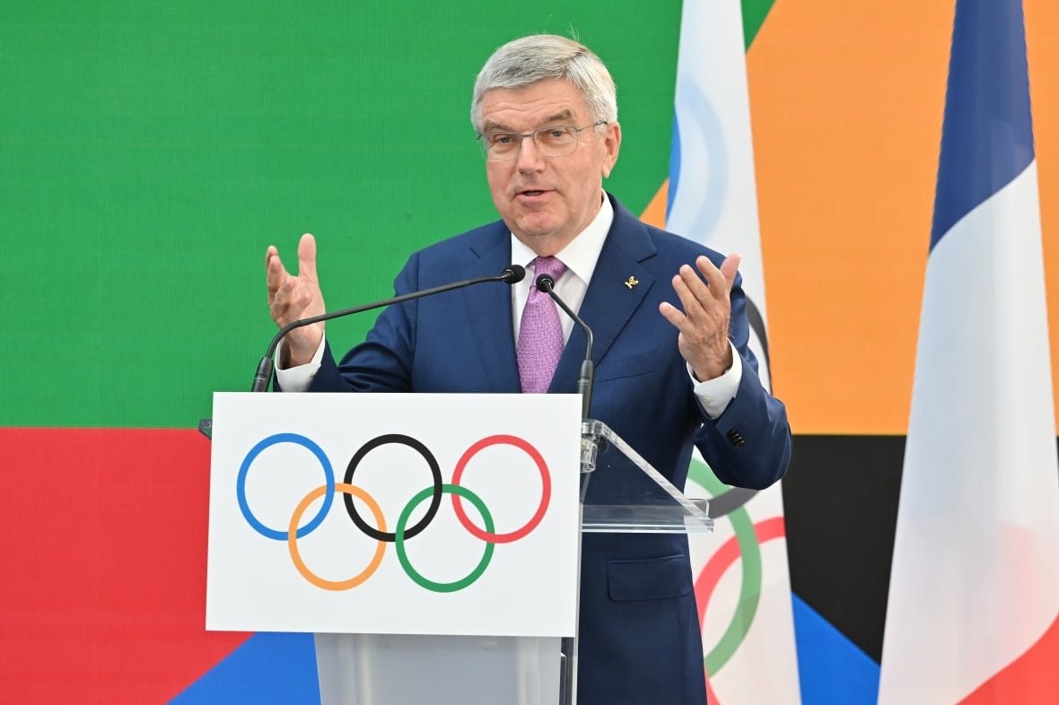 A man wearing a suit speaks behind a podium.