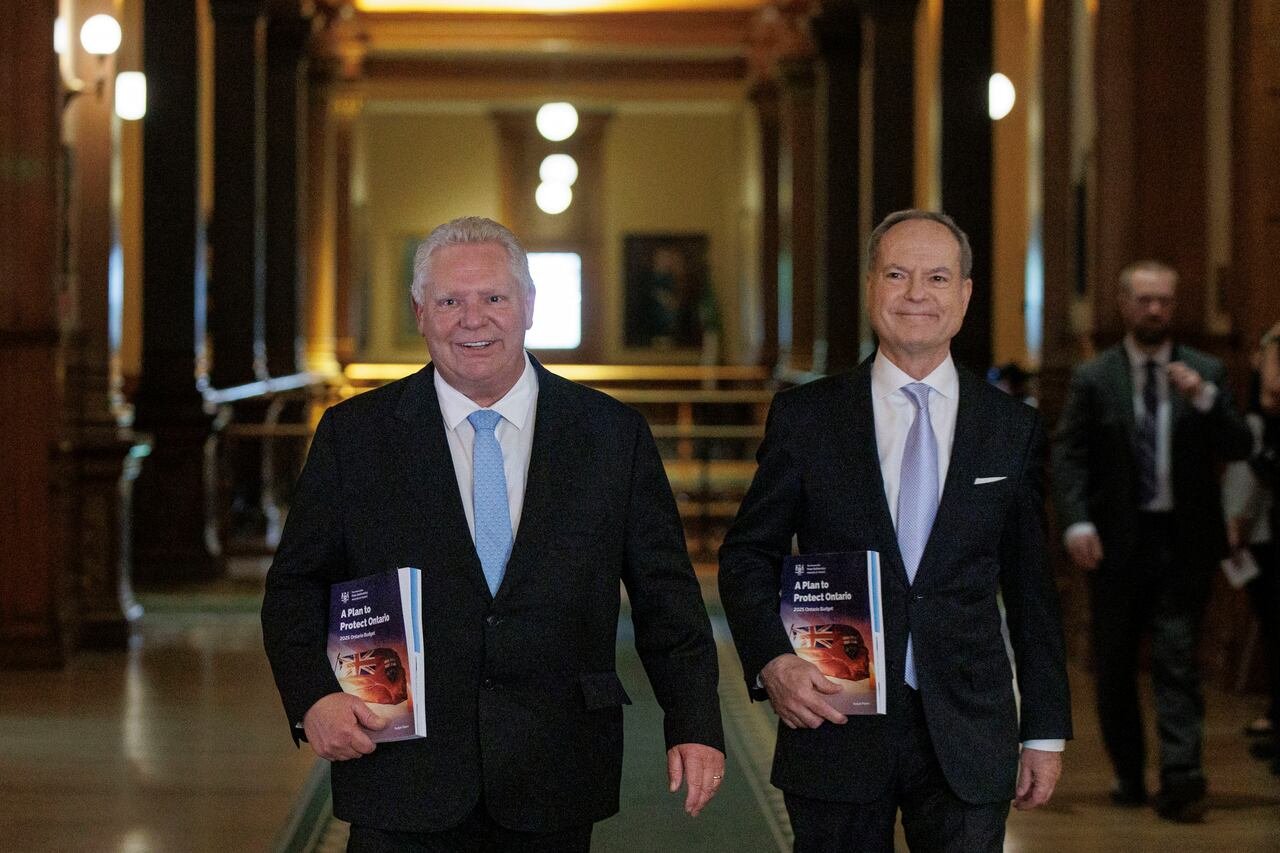 Two men walk side-by-side holding identical books.
