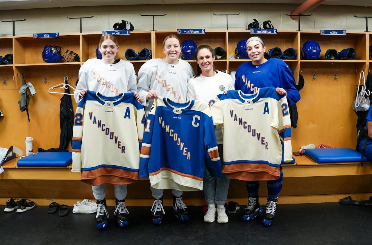 default-141 Four women pose with jerseys in their hands.