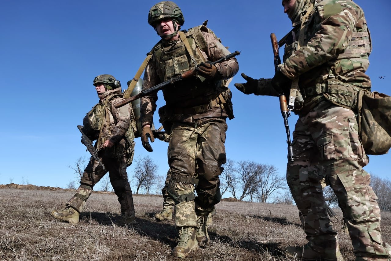 Individuals in camo, holding weapons