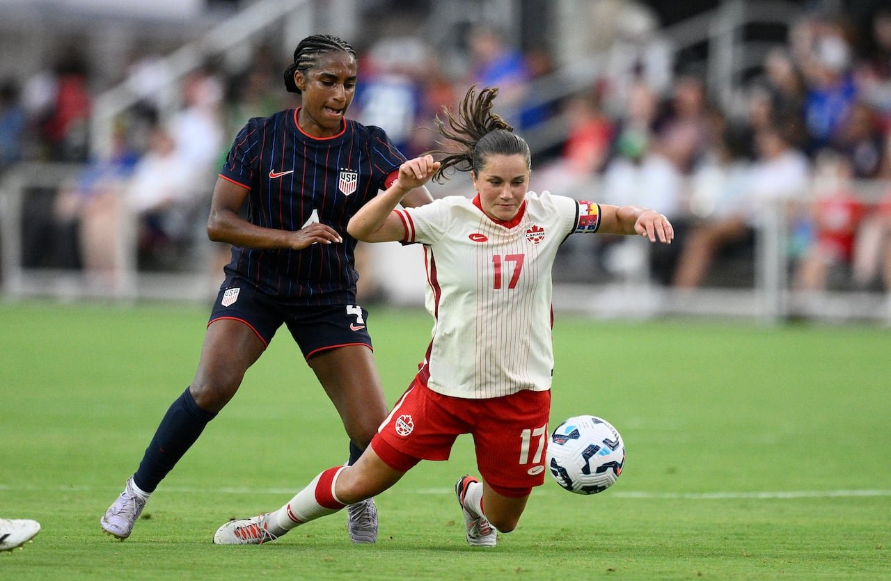 Two opposed soccer players battling for the ball.
